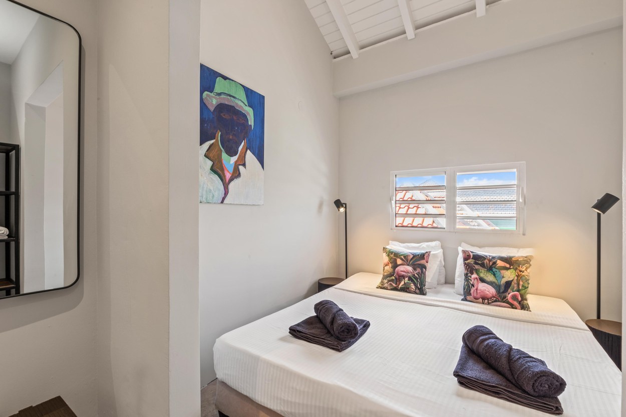 Zweites Schlafzimmer mit Queensize-Bett, Gemälde und Fenster über die Dächer