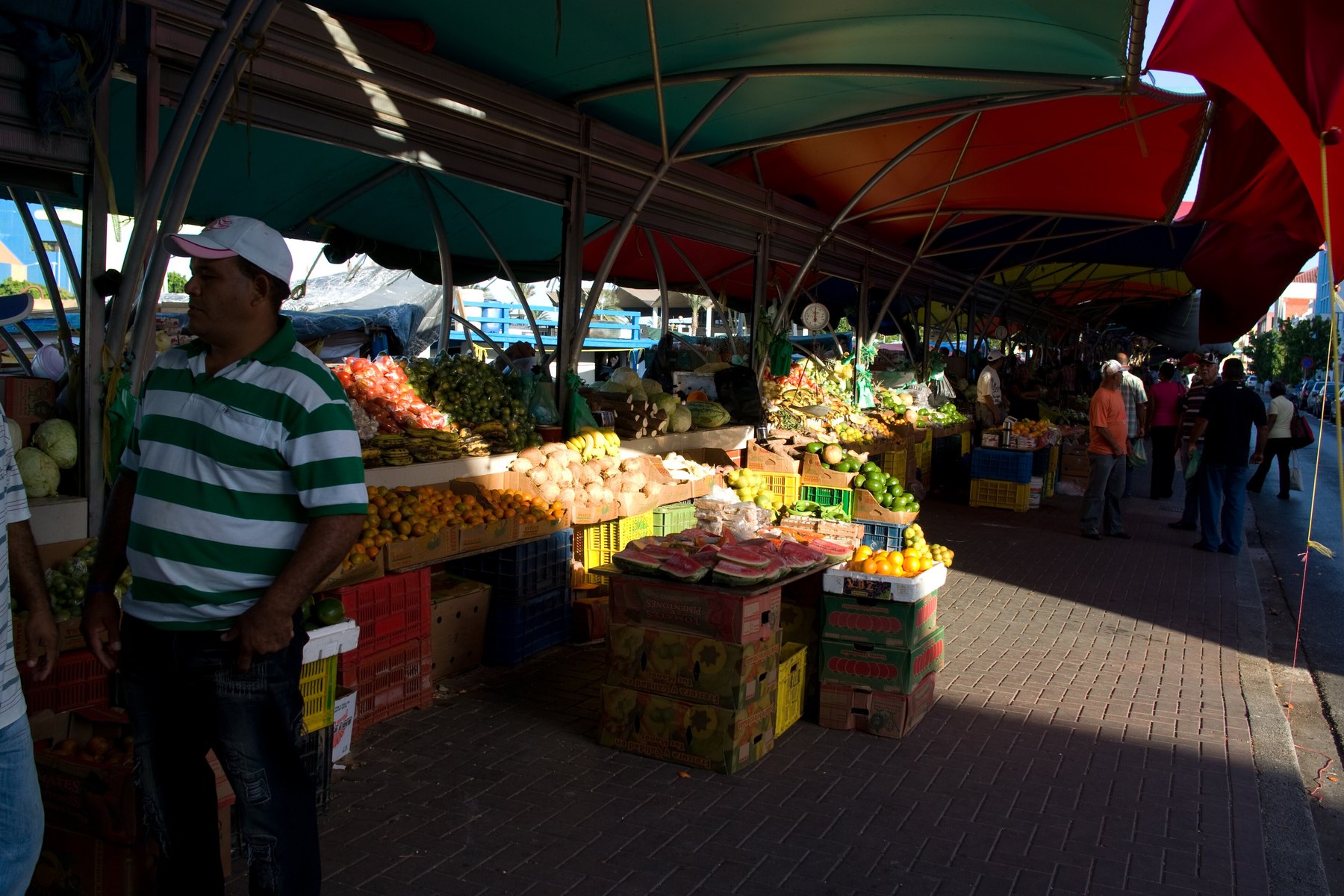 Stände mit frischem Obst und Gemüse unter bunten Planen auf dem schwimmenden Markt in Willemstad